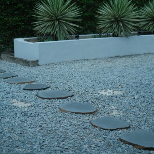 Circular stone pathway in a modern garden with agave plants and gravel.